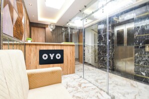 Ein Empfangsbereich mit einem Holztisch, einem Schild mit der Aufschrift 'OYO' und einem Marmorboden.