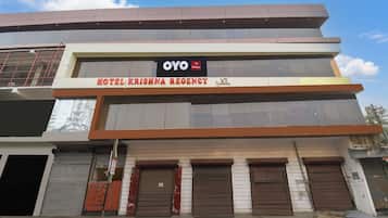 Ein mehrstöckiges Gebäude mit einem Schild für 'Hotel Krishna Regency' und einem Logo für 'OYO Hotel'.