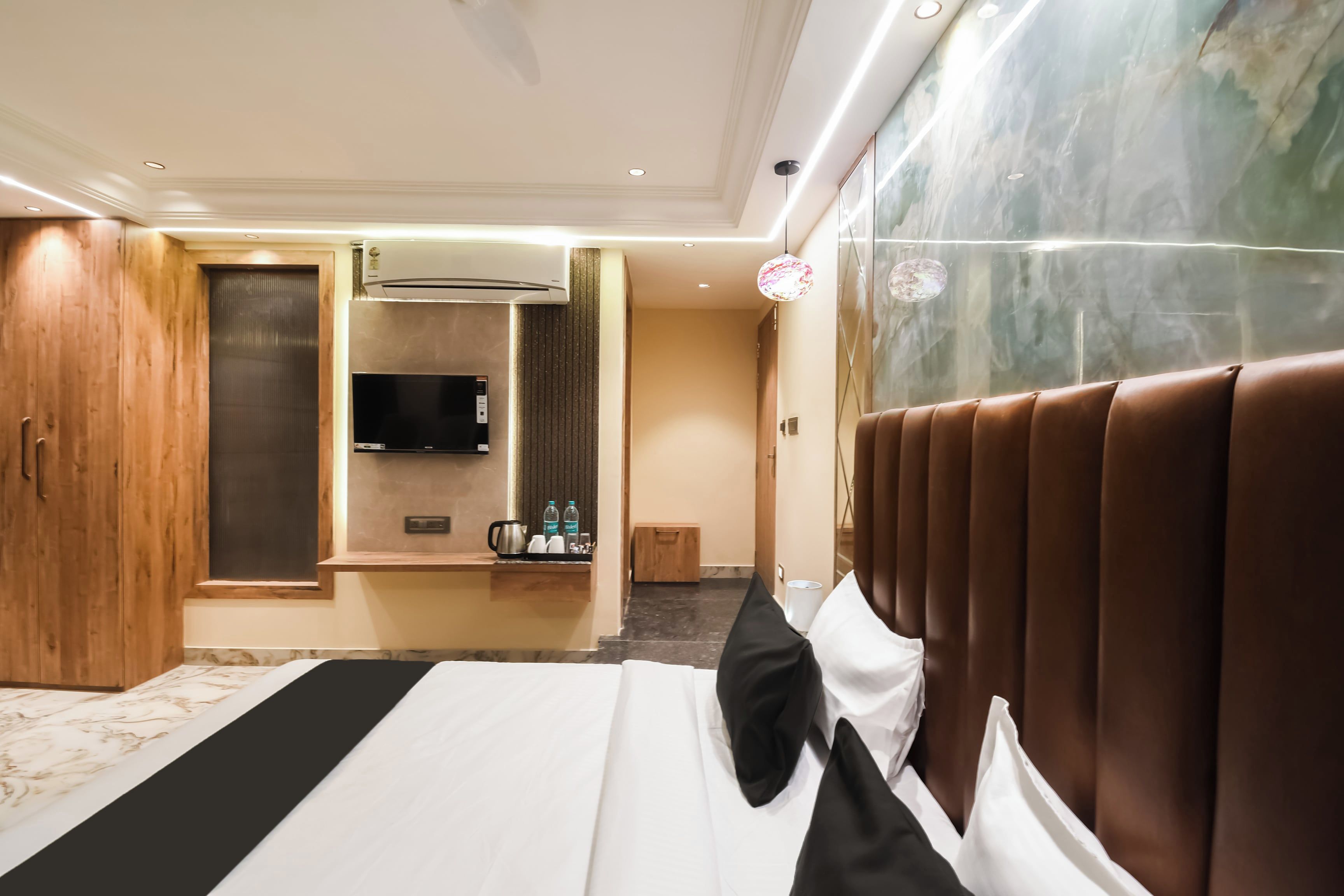 Een hotelkamer met een bed, een minibar, een televisie en een houten garderobe.