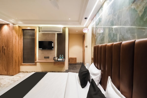 A hotel room with a bed, a minibar, a television, and a wooden wardrobe. - Hotel O Krishna Regency (Krishnanagar)