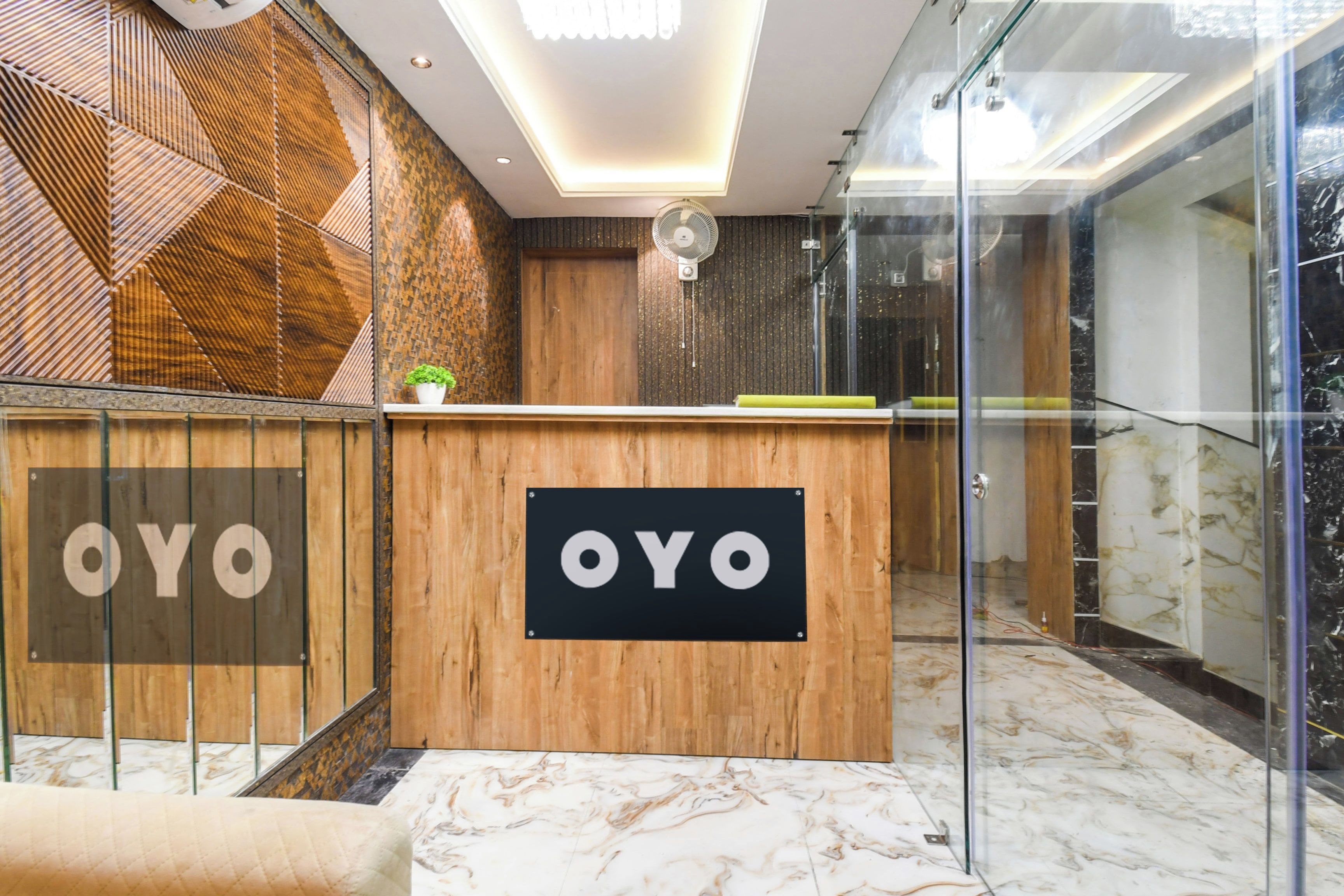 Een receptiebalie met 'OYO'-branding, een modern interieur met houten details en een glazen scheiding.