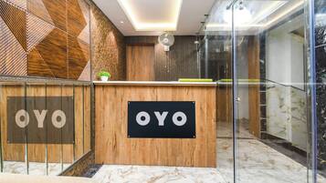 Een receptiebalie met 'OYO'-branding, een modern interieur met houten details en een glazen scheiding.
