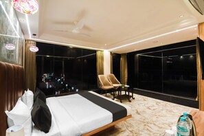 Ein Hotelzimmer mit Bett, Stuhl, Tisch und großen Fenstern mit Blick auf die Stadt.