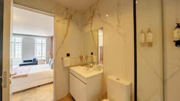 A modern bathroom with marble walls, a white sink, and a toilet.