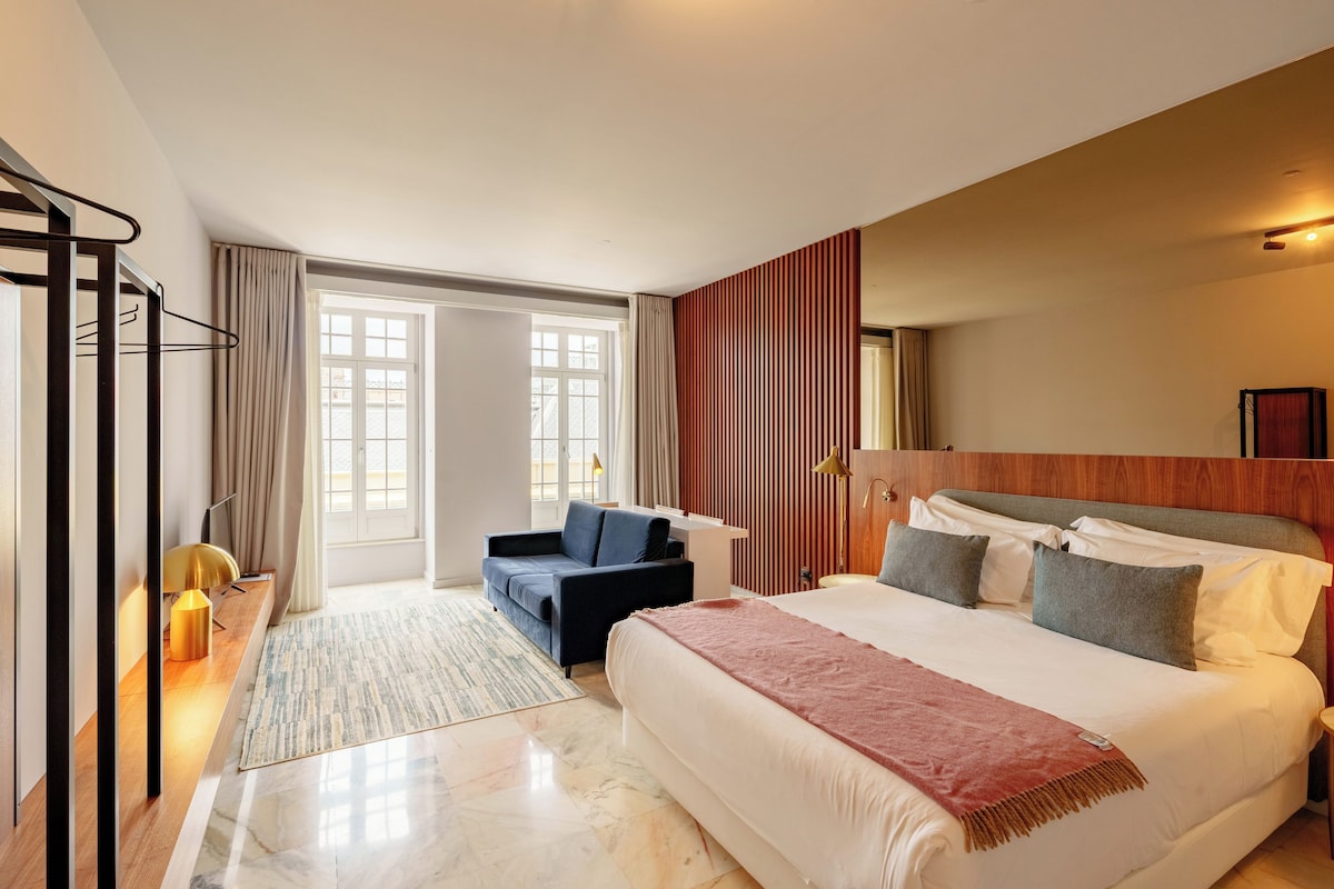 Une chambre d’hôtel avec un lit, un canapé, un bureau et une grande fenêtre.