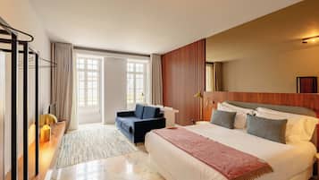 A hotel room with a bed, a sofa, a desk, and a large window.