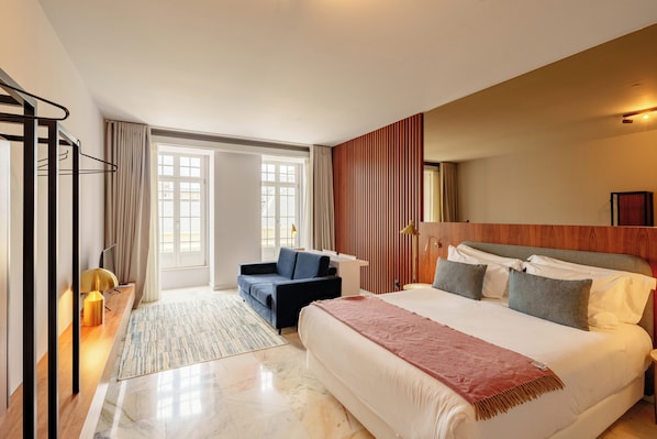 Une chambre d’hôtel avec un lit, un canapé, un bureau et une grande fenêtre.