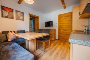 A modern kitchen with wooden cabinets, a granite countertop, and a built-in TV. - Chasa Patria Apartments (Ischgl)