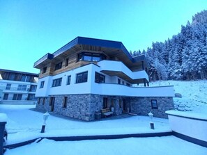 A modern multi-story building with a stone facade, large windows, and a flat roof. - Chasa Patria Apartments (Ischgl)