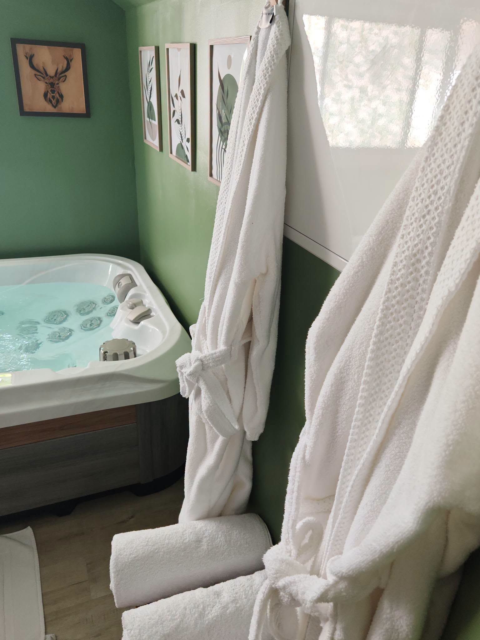 Une salle de bain avec une baignoire, des serviettes blanches et des œuvres d’art accrochées au mur.