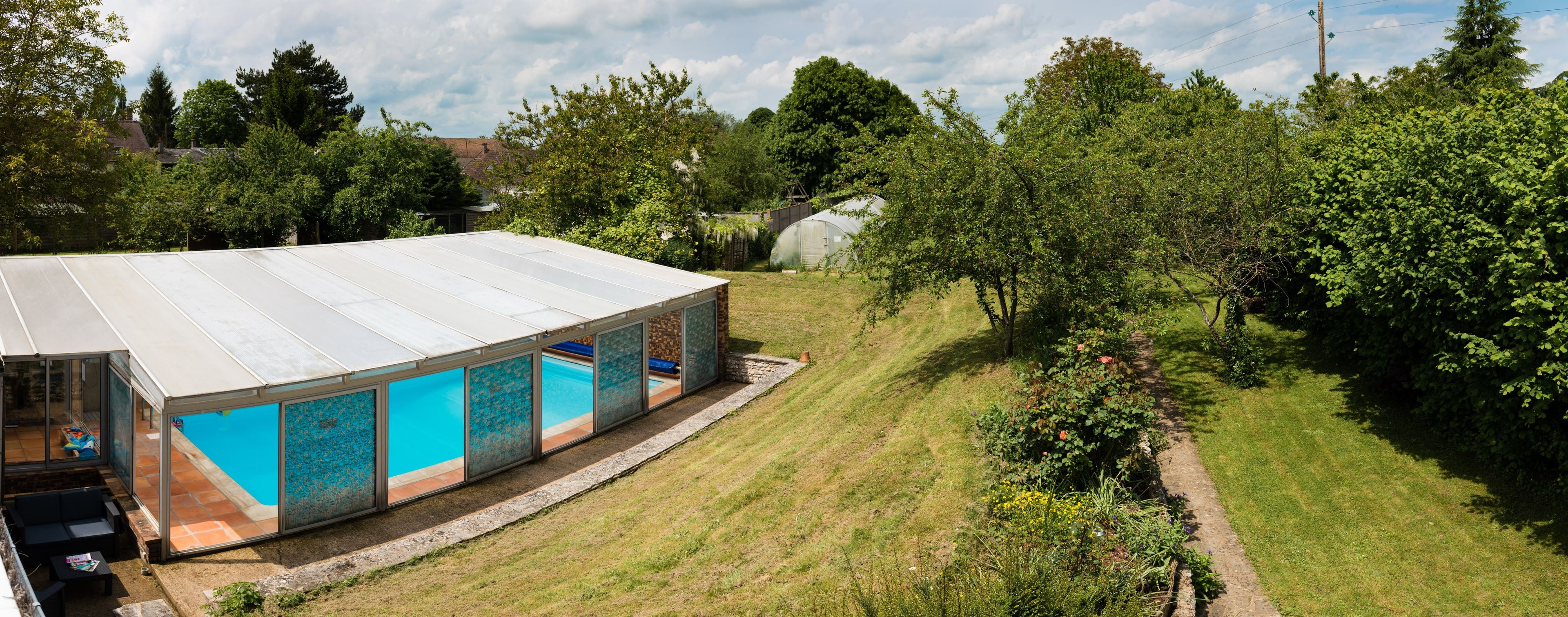 Ein modernes Gebäude mit überdachtem Schwimmbad und Garten.
