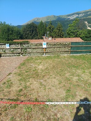 Ein Parkplatz mit einer Steinmauer und einem gepflasterten Weg, der zu einem Gebäude mit einem Ziegeldach führt.