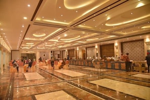 A spacious hotel lobby with a marble floor, a reception desk, and seating areas.