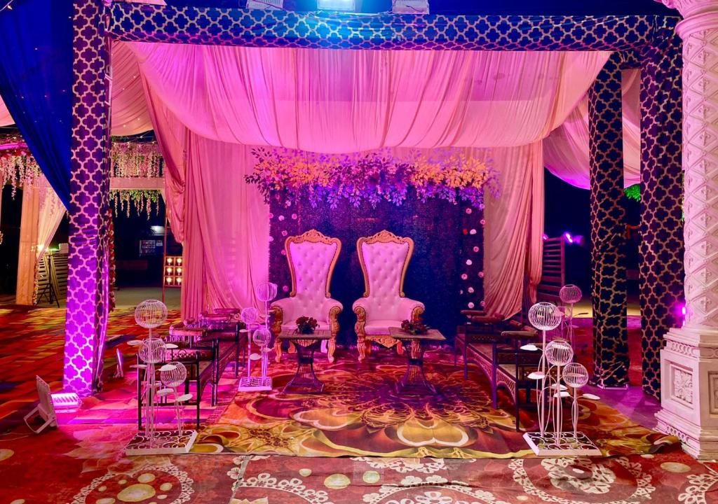 A stage with two ornate chairs, draped curtains, and floral arrangements.