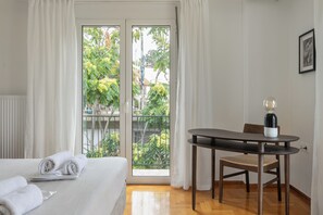 Ein Hotelzimmer mit einem Bett, einem Tisch mit Stuhl und Blick auf Grün.