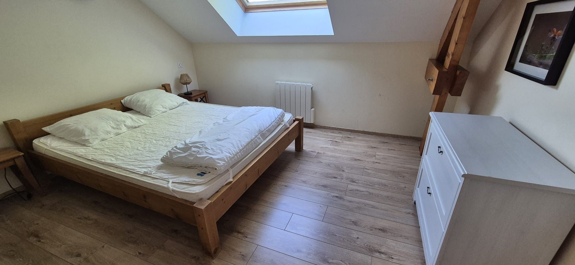A bedroom with a wooden bed, a radiator, a desk, and a wardrobe.