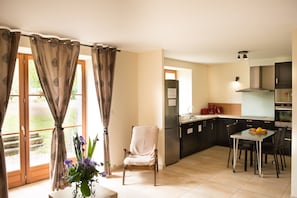 A modern kitchen with a refrigerator, stove, and dining area.