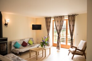 Una sala de estar con un sofá, una mesa de madera, una silla, un televisor y una chimenea.