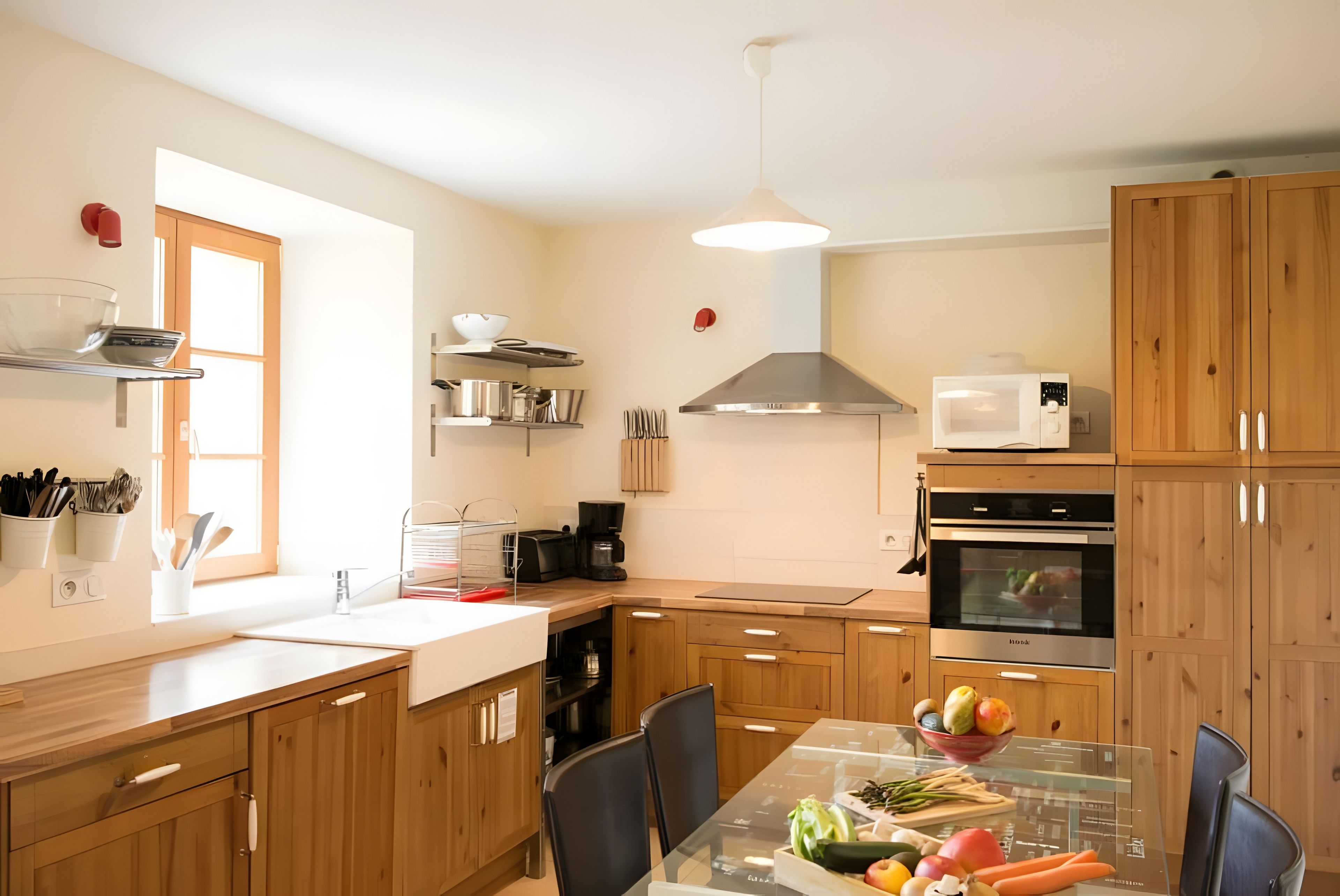 Eine moderne Küche mit Holzschränken, einem Glastisch und einem eingebauten Backofen.
