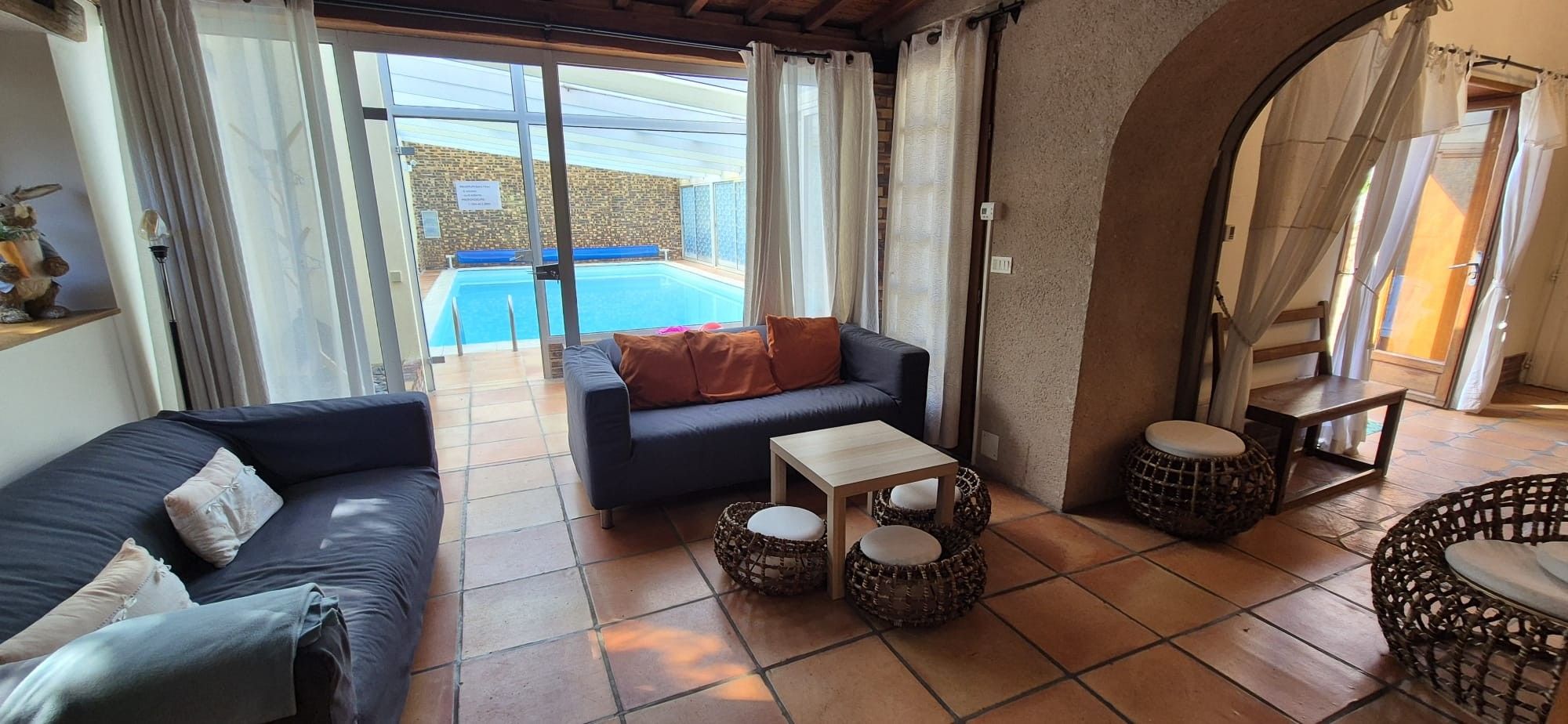 Ein Wohnzimmer mit einer Couch, einem Couchtisch und Blick auf einen Swimmingpool.