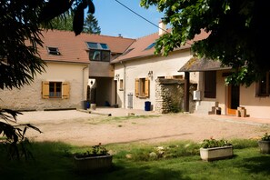 Ein zweistöckiges Gebäude mit Ziegeldach, Steinmauer und einem Kieshof.