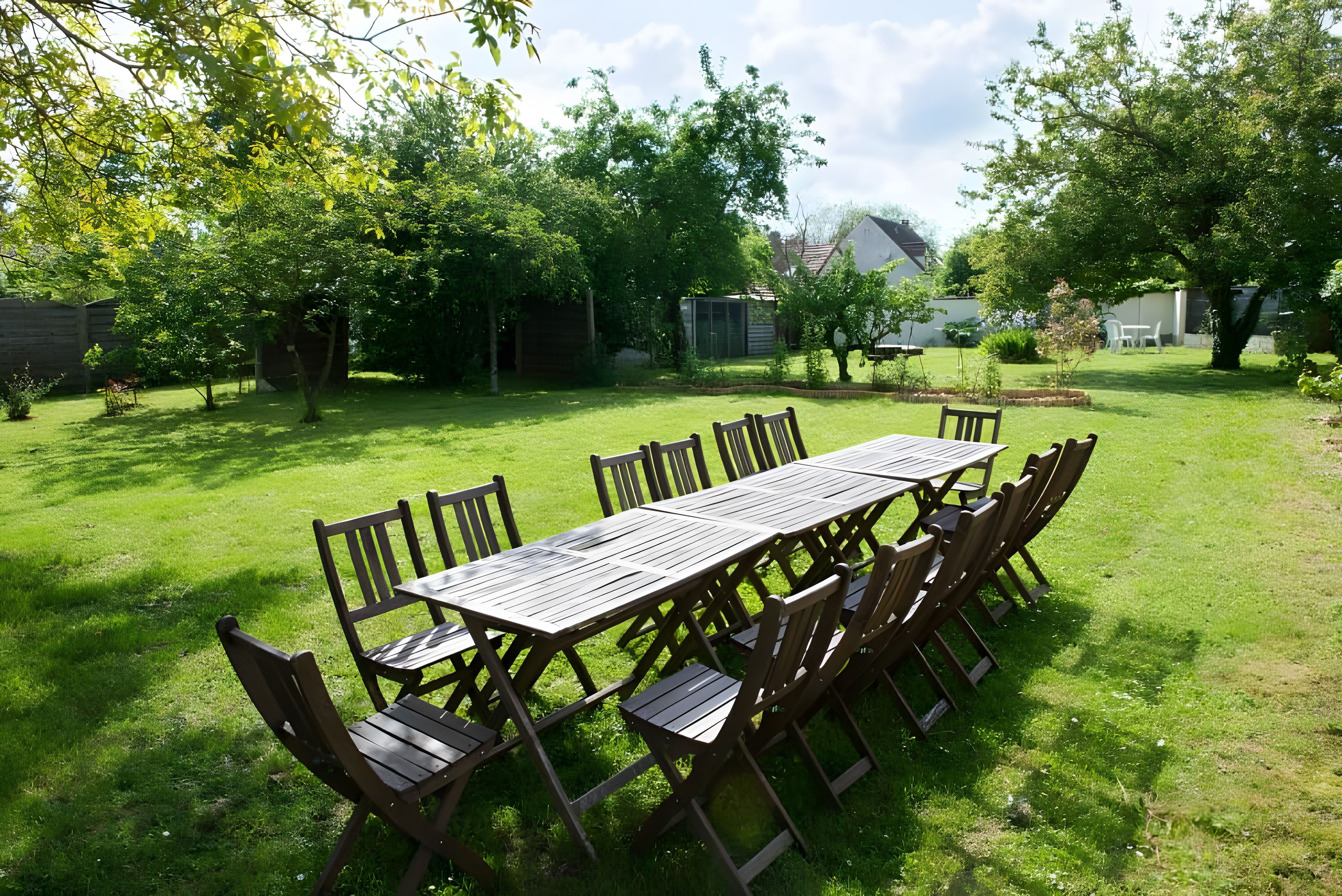 A rectangular wooden table with chairs in a grassy backyard.