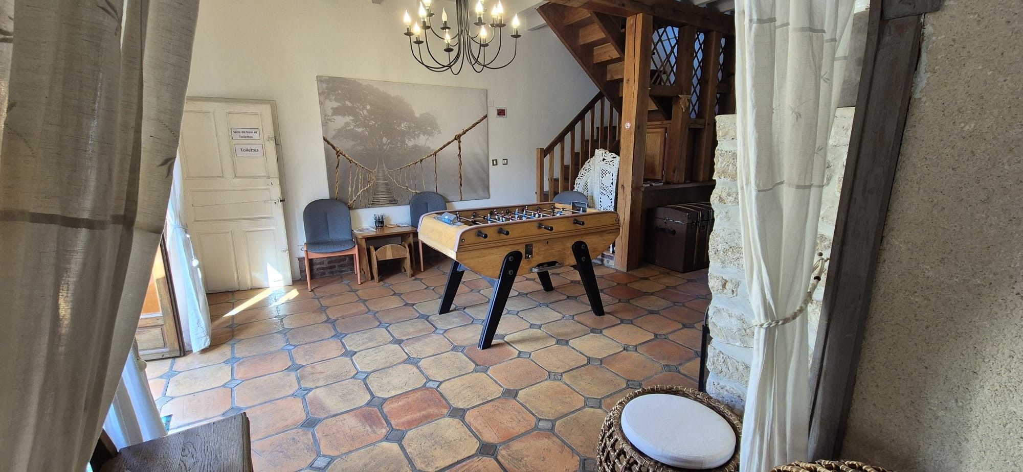 Quarto com mesa de futebol, cadeira de madeira, escrivaninha e escada.