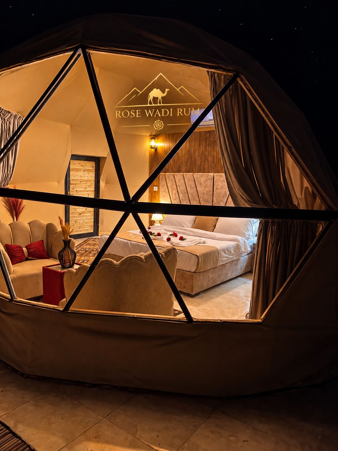 A tent with a bed, a sofa, and a small table with a vase.