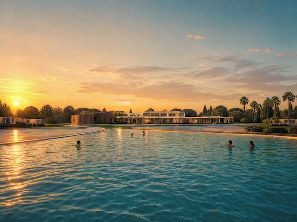 A swimming pool with people in the water, surrounded by buildings and palm trees.