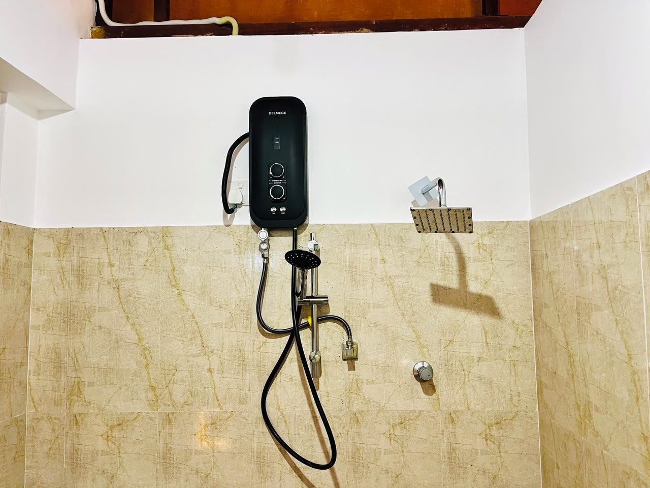 Un baño con ducha de mano, panel de control y rociador, todo instalado en una pared con azulejos.