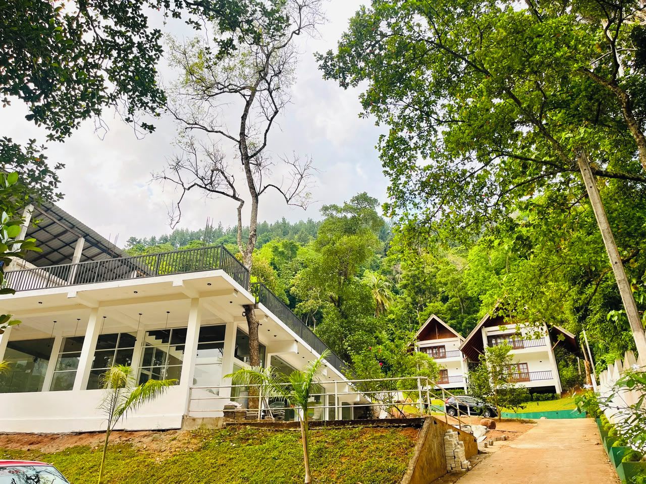 A modern building with a balcony, surrounded by lush greenery and trees.