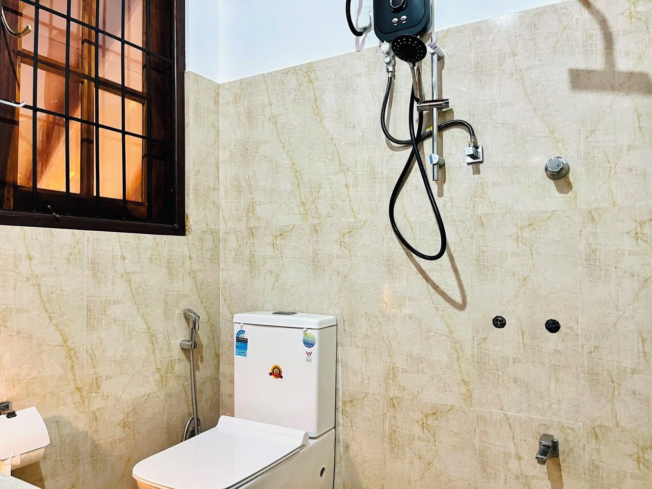 A bathroom with a toilet, a sink, and a shower unit.