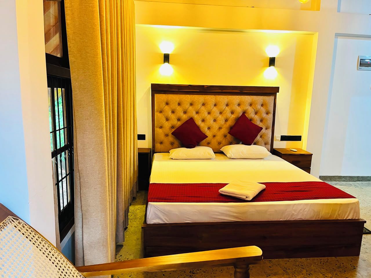 A hotel room with a large bed, a wooden headboard, and two bedside lamps.