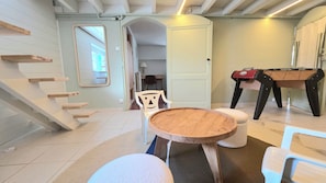 A room with a wooden staircase, a round wooden table, a white chair, and a grill. - New Listing (Royan)