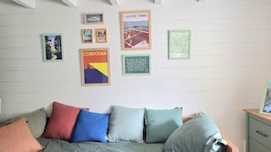 A room with a bed, pillows, and a wall decorated with framed pictures. - New Listing (Royan)