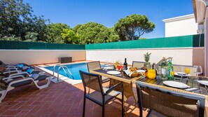 A rooftop pool area with lounge chairs, a dining table set for breakfast, and a clear view of the surrounding greenery. - Pine Haven. Vale do Lobo 3 Bedroom Townhouse (Vale do Lobo)