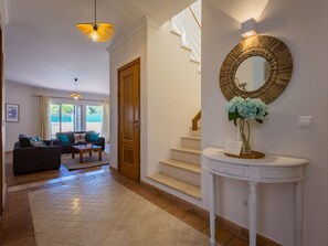 A spacious living area with a sofa, a coffee table, and a staircase leading to an upper floor. - Pine Haven. Vale do Lobo 3 Bedroom Townhouse (Vale do Lobo)