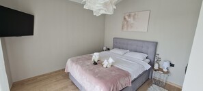 A bedroom with a bed, bedside tables, a wall-mounted TV, and a painting. - Villa La Vie with heated pool (Garica)