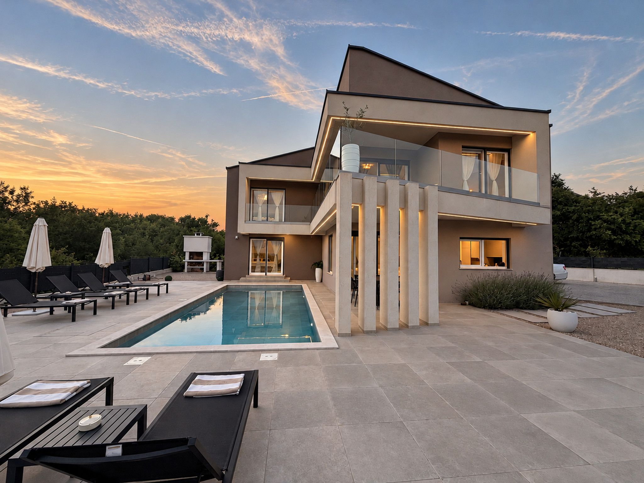 A modern two-story building with a swimming pool, outdoor seating, and a clear sky.