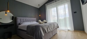 A bedroom with a bed, a round mirror, a chair, and a window with sheer curtains. - Villa La Vie with heated pool (Garica)