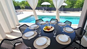 A dining table set for six with a pool view, surrounded by chairs with a lattice design. - Villa La Vie with heated pool (Garica)