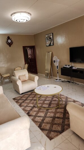 A living room with a sofa, armchair, coffee table, and a flat-screen TV. - New Listing (Abidjan)