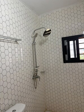 A bathroom with a shower, toilet, and a window with a view. - New Listing (Abidjan)