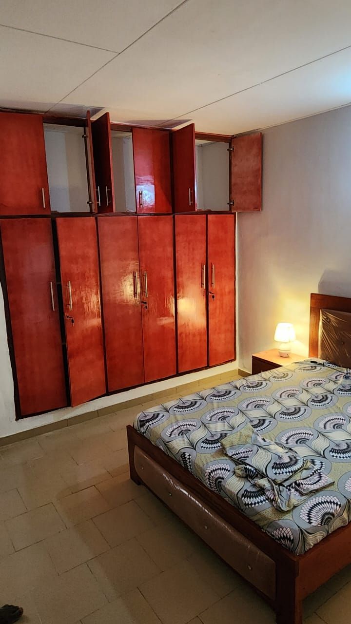 A bedroom with a bed, a wardrobe, and a nightstand with a lamp.