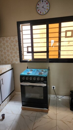 A kitchen with a gas stove, oven, and a window with blinds. - New Listing (Abidjan)