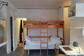 A bunk bed room with a desk and chair, a ladder, and a small shelf with items. - New Listing (Arvika)