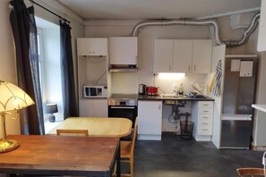 Pieni, käytännöllinen keittiö, jossa on valkoiset kaapit, mikroaaltouuni, liesi ja jääkaappi.