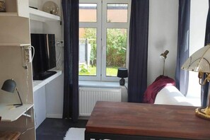 A room with a window, a radiator, a table, and a lamp. - New Listing (Arvika)