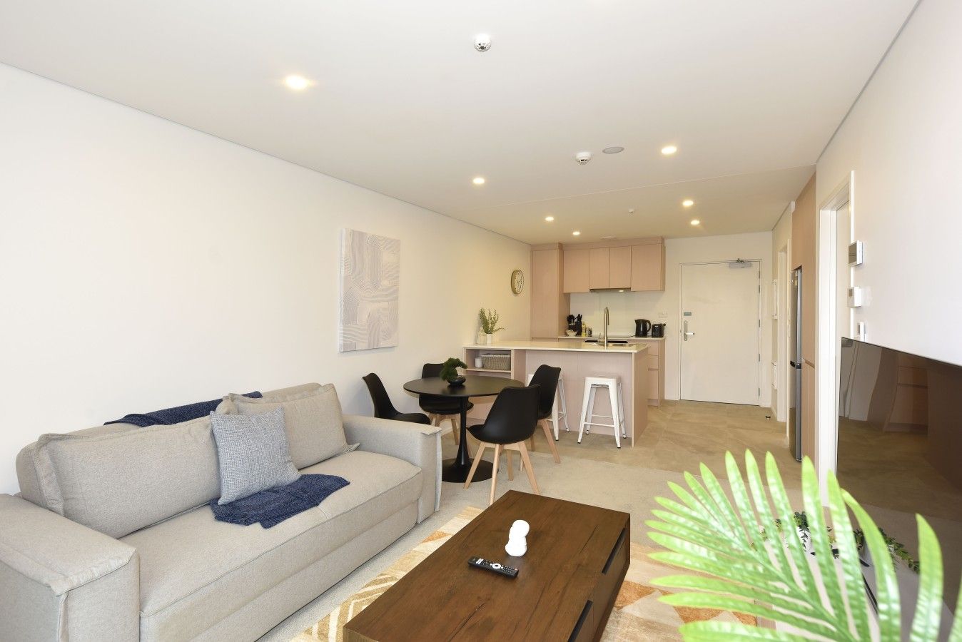 A modern living room with a sofa, coffee table, and a dining area with chairs and a small table.