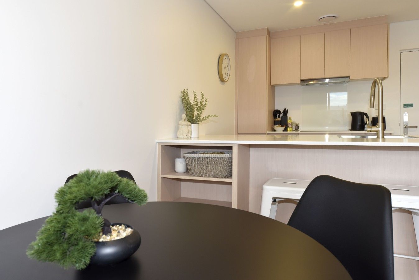 Une cuisine moderne avec une table ronde, des chaises, une horloge et une petite plante en pot.
